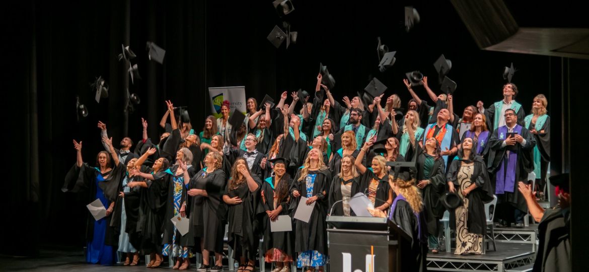 Image of Geraldton Universities Centre's 2024 graduating class, throwing their graduation caps into the air with joy